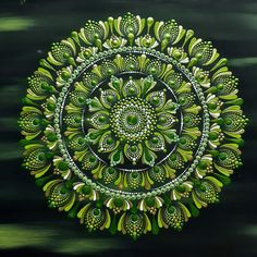 a green and white circular design painted on a black background with lots of small leaves