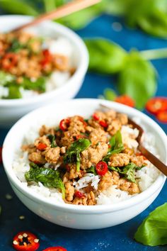 two white bowls filled with rice, meat and veggies on a blue surface