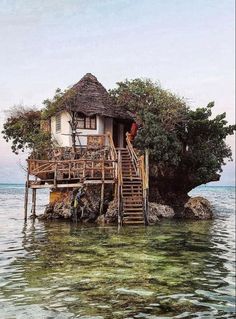 a house on an island in the middle of the ocean with stairs leading up to it