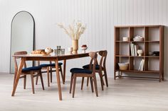 a dining room table and chairs with bookshelf in the back ground next to it