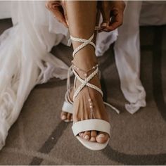 a woman wearing white shoes with straps on her feet and one foot in the air