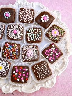 a white plate topped with lots of chocolates covered in sprinkles and hearts