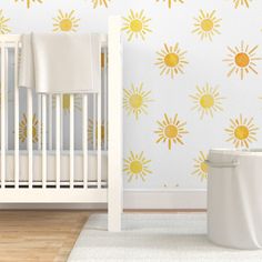 a white crib in front of a wall with yellow sun decals