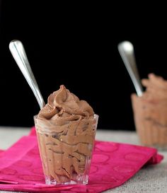 there are three spoons sticking out of a chocolate ice cream sundae on a pink napkin