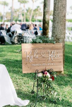 a wooden sign that says kyle and kate on it sitting in the grass next to a chair