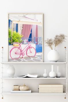 a white shelf with a pink bicycle on it and vases next to the shelves