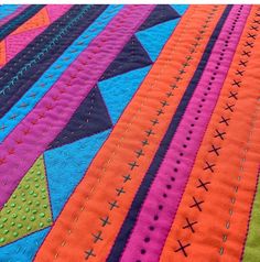 a colorful quilt is laying on top of a tablecloth with stitchs and crosses