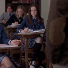 some people are sitting at desks in school uniforms