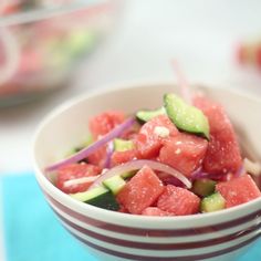 a white bowl filled with watermelon and cucumber on top of a blue place mat