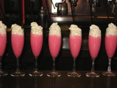 five glasses filled with pink liquid and whipped cream