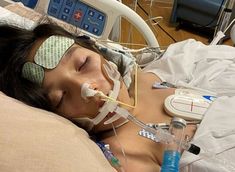 a woman laying in a hospital bed with an oxygen tube attached to her head and breathing apparatus