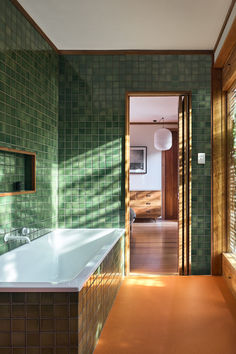 a bathroom with green tiled walls and wood trimmings on the wall, along with a large bathtub