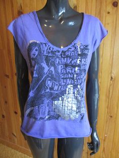 Vintage T-shirt, purple with a black and silver motif on the front and an unusual spiders web cut out back.  Dimensions: Chest: 35 Inches. Length: 22 Inches. Made in France Fitted Summer T-shirt With Graffiti Print, Vintage Graphic Print T-shirt For Alternative Fashion, Fitted Graffiti Print T-shirt With Crew Neck, Vintage Stretch T-shirt For Summer, Purple Grunge T-shirt With Letter Print, Purple Cotton Y2k T-shirt, Vintage Stretch T-shirt With Graphic Print, Fitted T-shirt With Vintage Print And Short Sleeves, Trendy Summer T-shirt For Alternative Fashion