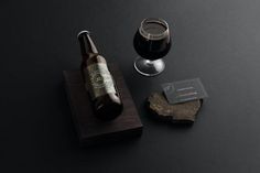 a bottle of beer next to a wine glass on a wooden block with a business card