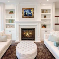 a living room filled with white furniture and a fire place in the middle of it