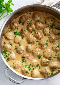 a pot filled with meatballs and gravy on top of a white counter