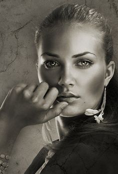 a black and white photo of a woman holding her hand up to her face,