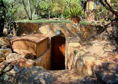 an outhouse built into the side of a rock wall with trees in the background