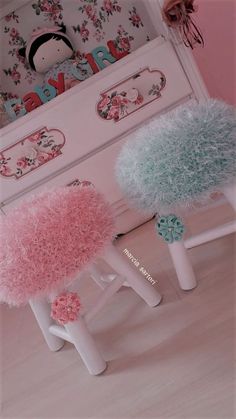 two stools with fuzzy pink and blue covers on them in front of a toy dresser