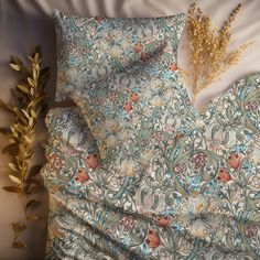 a close up of a bed with a flower and leaves on the pillow case next to it