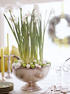 a vase filled with white flowers on top of a table next to glasses and candles