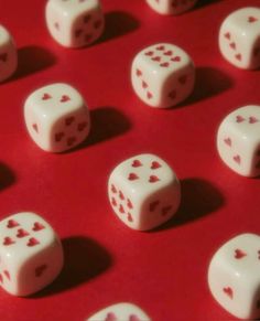 white dices with red hearts on them sitting on a red surface