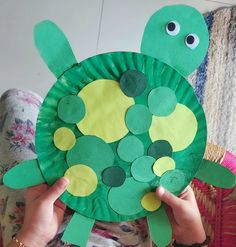 a person holding up a paper plate shaped like a turtle