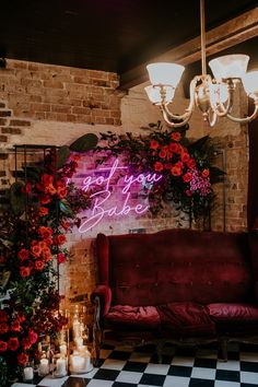 a red couch sitting in front of a brick wall with flowers and candles on it