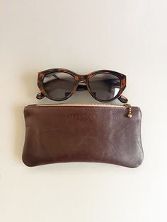 This brown leather sunglasses case is made with love. This pouch ensures your glasses stay safe and scratch-free with its secure zipper. A perfect blend of fashion and function, it's the ideal gift for anyone who appreciates style and practicality. Crafted with a stylish fabric lining, this leather case offers elegance and softness inside, while its versatile design allows it to double as a wallet. Classic Wayfarer Sunglasses For Everyday Use, Classic Brown Sunglasses For Travel, Rectangular Tinted Sunglasses For Everyday Use, Leather Sunglass Case, Leather Sunglasses Case, Zipper Purse, How To Make Handbags, Glasses Case, Spectacles