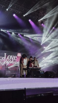 three people standing on stage with purple lighting