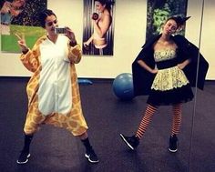 two women in costumes are taking pictures with their cell phones while one woman is dressed as a giraffe