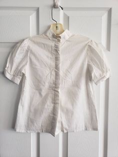 SALE This is a vintage Best of Friends size 12 girls short sleeve blouse. It is white on white stripes. It has buttons down the front. There are 3 belt loops on the collar, so I am guessing that at one point there could have been a ribbon that went around the neck. The measurements are as follows: (Make sure you check measurements as I do not accept returns.) Shoulders: 11.75 inches Armpits: 16 inches across Sleeves: 8.5 Inches Sleeve Opening: a hair shy of 4.75 inches Hem: 18 inches Length from Classic White Short Sleeve Shirt With Buttons, White Blouse With Button Closure And Short Sleeves, Retro Short Sleeve Blouse With Buttons, White Retro Shirt For Daywear, Retro Short Sleeve Button Blouse, Vintage Style White Shirt For Work, Vintage White Shirt For Work, White Short Sleeve Blouse With Button Closure, White Short Sleeve Retro Shirt