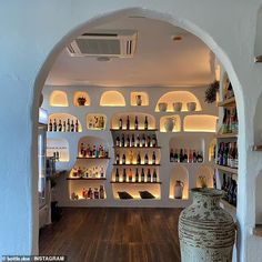 an archway leading into a wine cellar with bottles on the wall and shelves full of liquor