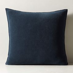 a dark blue pillow sitting on top of a white table next to a black wall