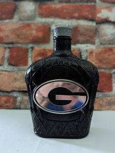 a bottle of black liquid sitting on top of a white table next to a brick wall