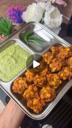 a person holding a tray filled with food and dipping sauce on top of it's side