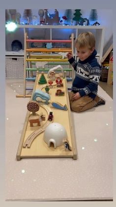 a young boy playing with his toy train set