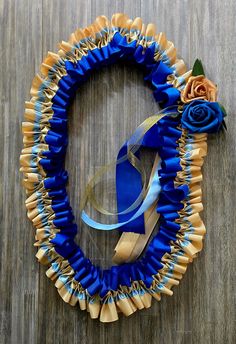 a wreath made out of blue ribbon with a rose on it sitting on top of a wooden table