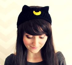 a young woman wearing a black cat hat with yellow eyes looking at her cell phone