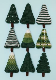 knitted christmas trees are arranged in rows on a blue background, one is green and the other is white