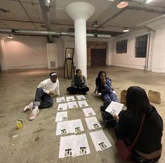 three people sitting on the floor with papers in front of them