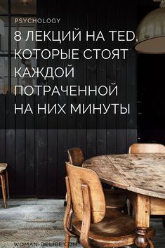 a wooden table and chairs in front of a black wall with words written on it