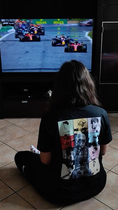 a person sitting on the floor in front of a tv playing a game with remote controllers