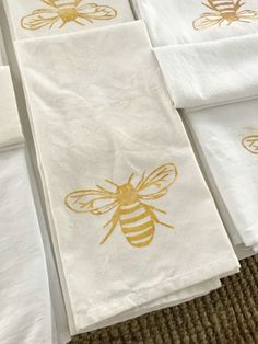 six white towels with gold bee designs on them