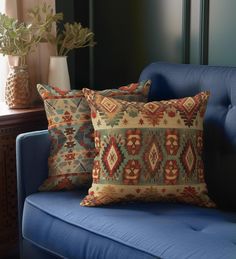 two pillows sitting on top of a blue couch next to a vase filled with flowers