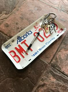 a license plate that has been decorated with keys and other things attached to it, sitting on a stone floor