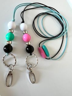 three necklaces with different colored beads are on a white table next to each other