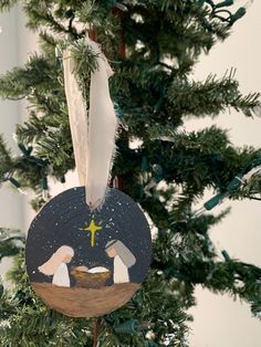 a christmas ornament hanging from the top of a tree with angels in it