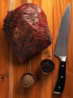 a large piece of meat sitting on top of a wooden table next to two small bowls