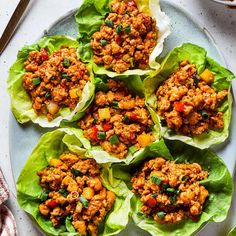 lettuce wraps filled with meat and vegetables on a white plate next to a fork